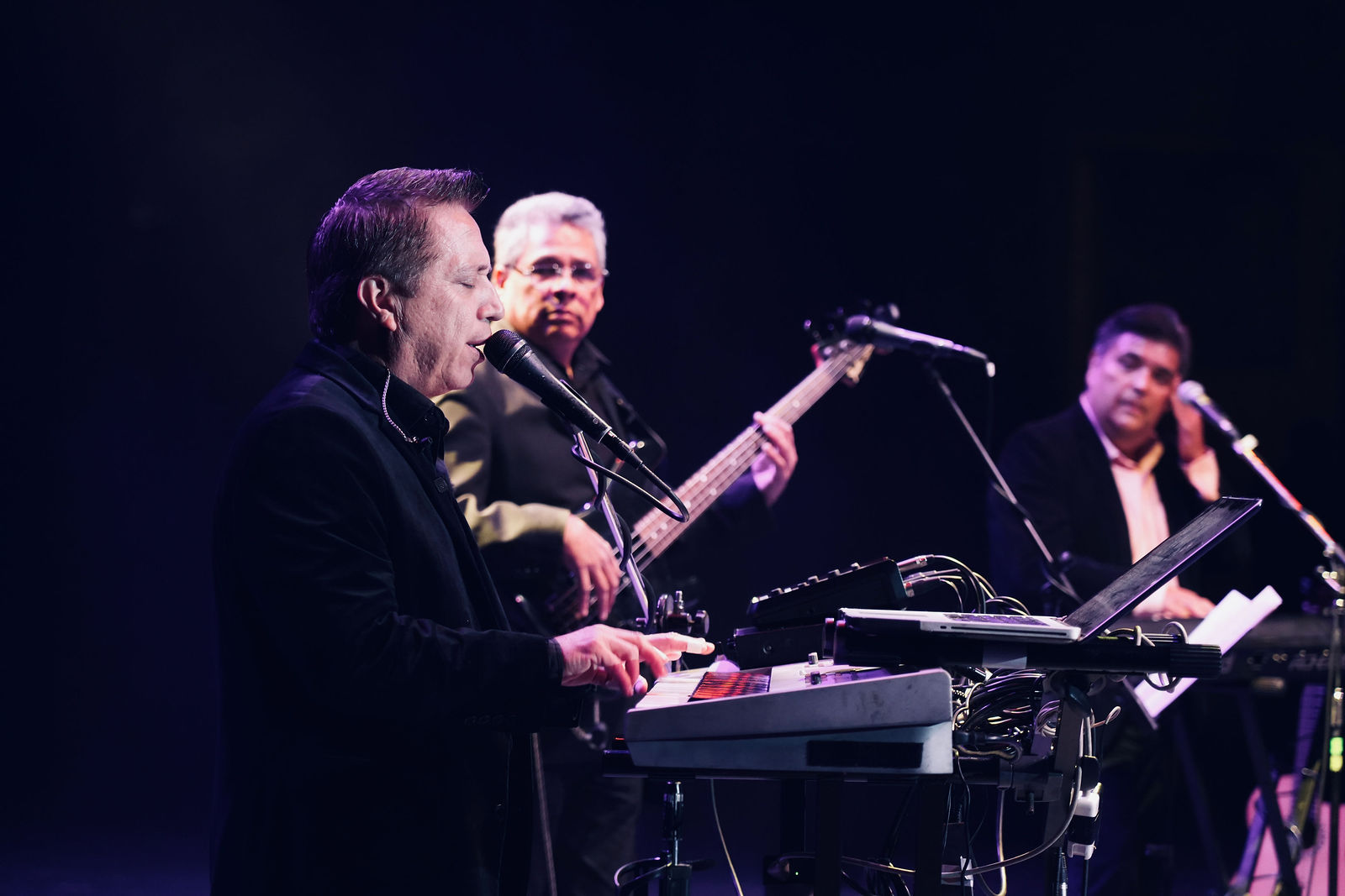 Alejandro Tornero performing with his band on a dark concert stage